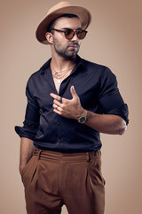 Beautiful brutal tanned hipster man in a black shirt, hat and glasses