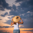 Girl in hat looking in sunset sky