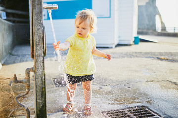 Wall Mural - Adorable toddler girl playing with water tap outdoors