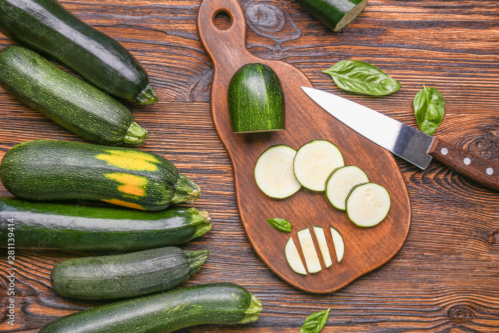Fresh zucchini, knife and cutting board on wooden background