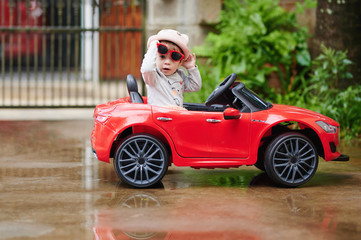 pretty baby girl in red toy car