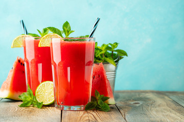 Watermelon slushie with lime and mint, summer refreshing drink in tall glasses on a light blue background. Sweet cold smoothie with copy space