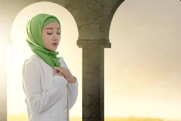 Wall Mural - Asian Muslim woman in a veil standing and praying