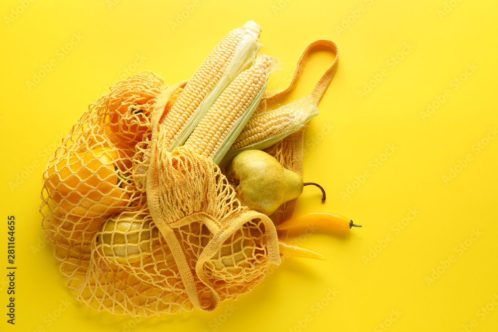 Mesh eco bag with products on color background