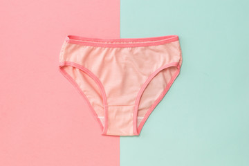 Pink women's panties on blue and pink background. The concept of meeting lovers. Underwear. The view from the top.