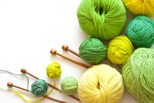 Colorful Green Balls Of Yarn For Hand Knitting And Wooden Needles On A White Background. On Left Empty Space For Text. Flat Lay, Close Up, Macro. Crafts And Hobbies