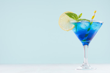 bright summer fresh blue fruit cocktail with blue curacao liquor, ice cubes, lemon slice, green mint