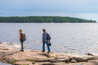© Tatyana_Andreyeva - Middle aged man and young lady walking on northern lake shore in summer day. Tourists against picturesque landscape. Travelling and discovering distant places of Earth. Onega lake, Karelia, Russia