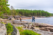 © Tatyana_Andreyeva - Middle aged man and young lady walking on northern lake shore in summer day. Tourists against picturesque landscape. Travelling and discovering distant places of Earth. Onega lake, Karelia, Russia