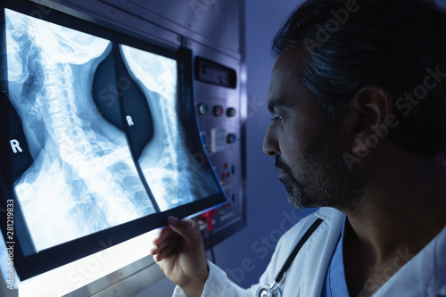 Fotografía Mature male doctor examining x-ray on x-ray light box in operation room at hospi