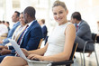 © WavebreakMediaMicro - Young Caucasian female executive using laptop in conference room, smiling to camera