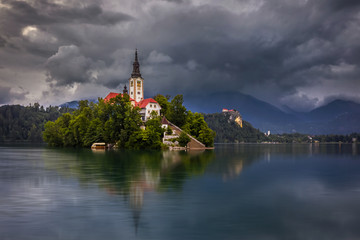 Wall Mural - Bled, Slovenia - Beautiful cloudy morning at Lake Bled (Blejsko Jezero) with the Pilgrimage Church of the Assumption of Maria and Bled Castle and Julian Alps at background at summer time