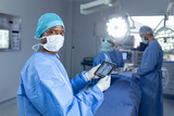 Fototapeta  - Male surgeon holding digital tablet in operation theater at hospital
