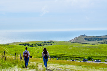 Two friends hiking along a cliff path with an ocean background in summer