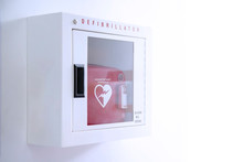 Automated External Defibrillator (AED) In White Box On The Wall Is An Emergency Pacemaker Device For People With Cardiac Arrest. Heart Defibrillator On White Background.