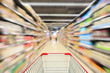 © Kwangmoozaa - Red Shopping cart view with supermarket aisle shelves interior abstract blur defocused background