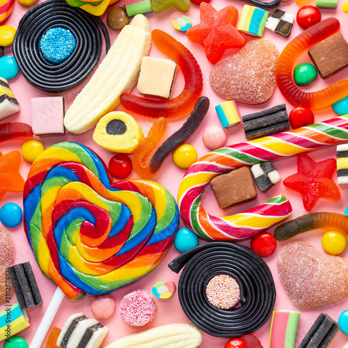 top view of assortment colourful lollipops and candies on pink like backgroun...