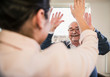 © Westend61 - Happy senior man with raised hands looking at young woman