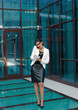 © splitov27 - All in work. Young Afro business woman talking on the phone and writing important information into notebook on the background of the business center