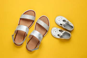 Kids and adults fashionable sandals on a yellow background. Top view