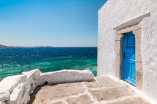 Mykonos, Greece. Traditional White Building With Blue Door At The Seaside.