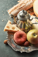 Different Juicy Fruits, Baguette, Cheese, Teapot In An Old Metal