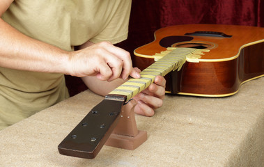 Wall Mural - Guitar repair and service - Worker polishing guitar neck frets acoustic guitar sandpaper