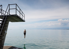 Rear View Of Boy Jumping From Diving Platform Into Lake