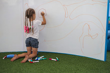 A Little Girl With Pigtails Drawing On The Wall