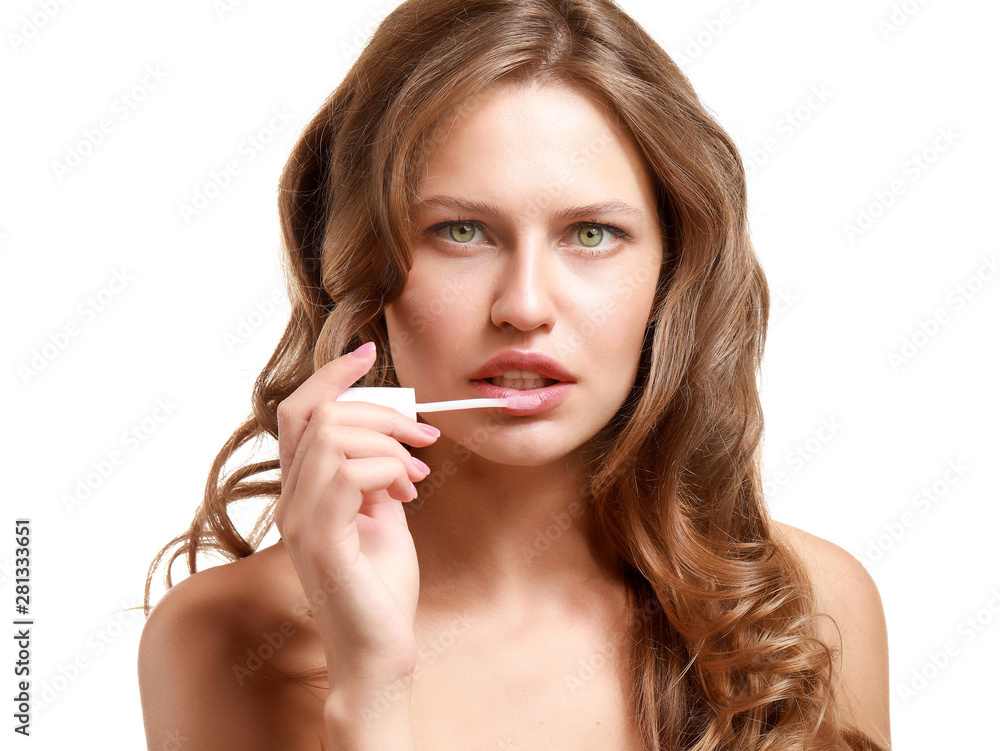 Beautiful young woman applying lipstick against white background