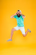 Happy music. Happy hipster jumping on music on yellow background. Bearded man enjoying song playing in headphones with smile on happy face. Happy fun and upbeat