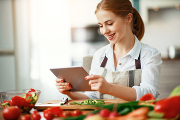 happy woman preparing vegetables in kitchen on prescription with tablet