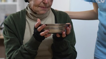 Wall Mural - Volunteer giving plate with food for homeless woman in care center, charity