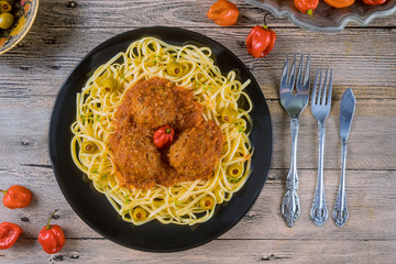 Wall Mural - Spaghetti and meatballs with tomato sauce in black dish on wooden background