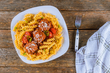 Wall Mural - Rotini pasta with meatballs in tomato sauce and olives in bowl.