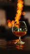 Cognac brandy in typical snifter on background of bright lights. Traditional French drink. Service and catering concept