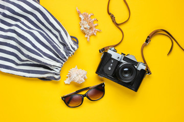 Traveler accessories, retro camera on a yellow background. Trip on the beach, vacation. Summer minimalistic background. Flat lay tourism allegory..Top view