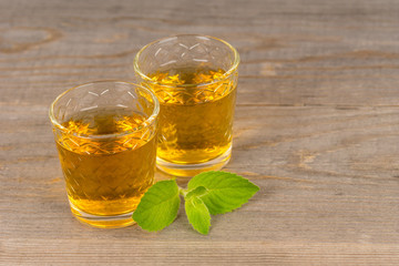 two glasses with homemade sweet wine with mint on wooden table