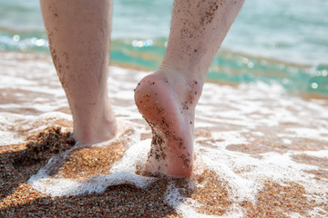 Closeup of bare feet on the beach. Walking on the sand at the water's edge. Vacation and travel concept. Men's feet.