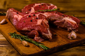 Raw ribeye steak, spices, rosemary and garlic on cutting board