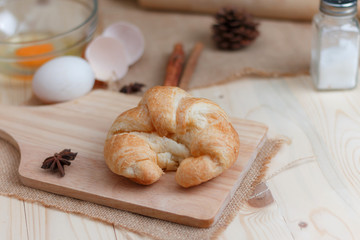 Croissant on wooden cut board on table wood and fabric select focus shallow depth of field