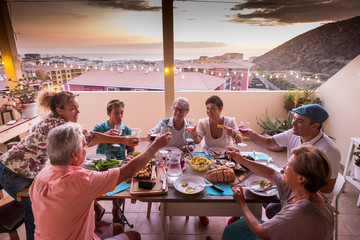 Wall Mural - Family and friends group of diversity ages people have fun all together clinking and toasting with wine glasses - old and young men and women laugh and smile together during celebration at home