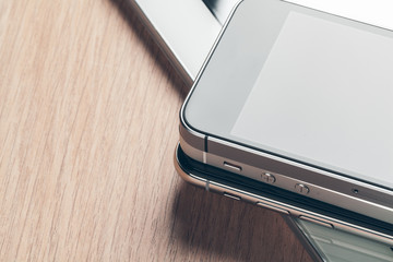 Digital tablet and mobile phone. Electronic devices on wooden table, close up.