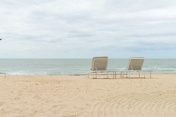 empty two beach chairs on a beautiful beach at sunny day - vacation in summer time