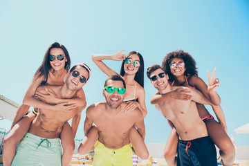 Wall Mural - Low angle photo of charming ladies guys piggybacking making v-signs wearing eyeglasses eyewear outdoors