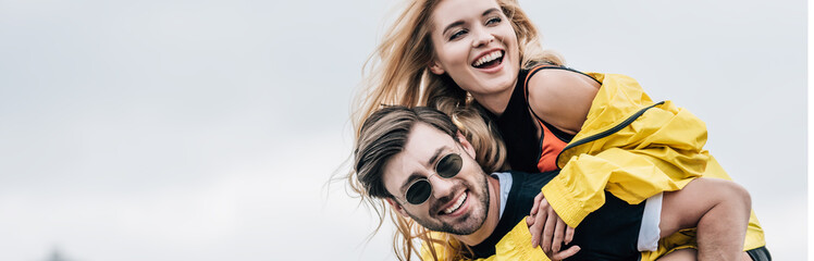 panoramic shot of attractive and blonde woman and handsome man hugging and playing on roof