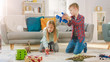© Gorodenkoff - In the Living Room: Boy and Girl Playing with Toy Airplanes and Dinosaurs while Sitting on a Carpet. Sunny Living Room with Children Having Fun.