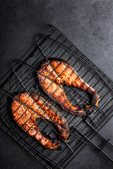 Wall Mural - Grilled salmon on iron grill grate on a dark background top view. BBQ seafood. spece for a text