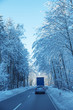 PKW fährt dicht hinter einem LKW auf winterlicher Straße durch den Wald. hochformat
