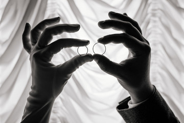 hands of the bride and groom hold wedding rings black and white silhouette